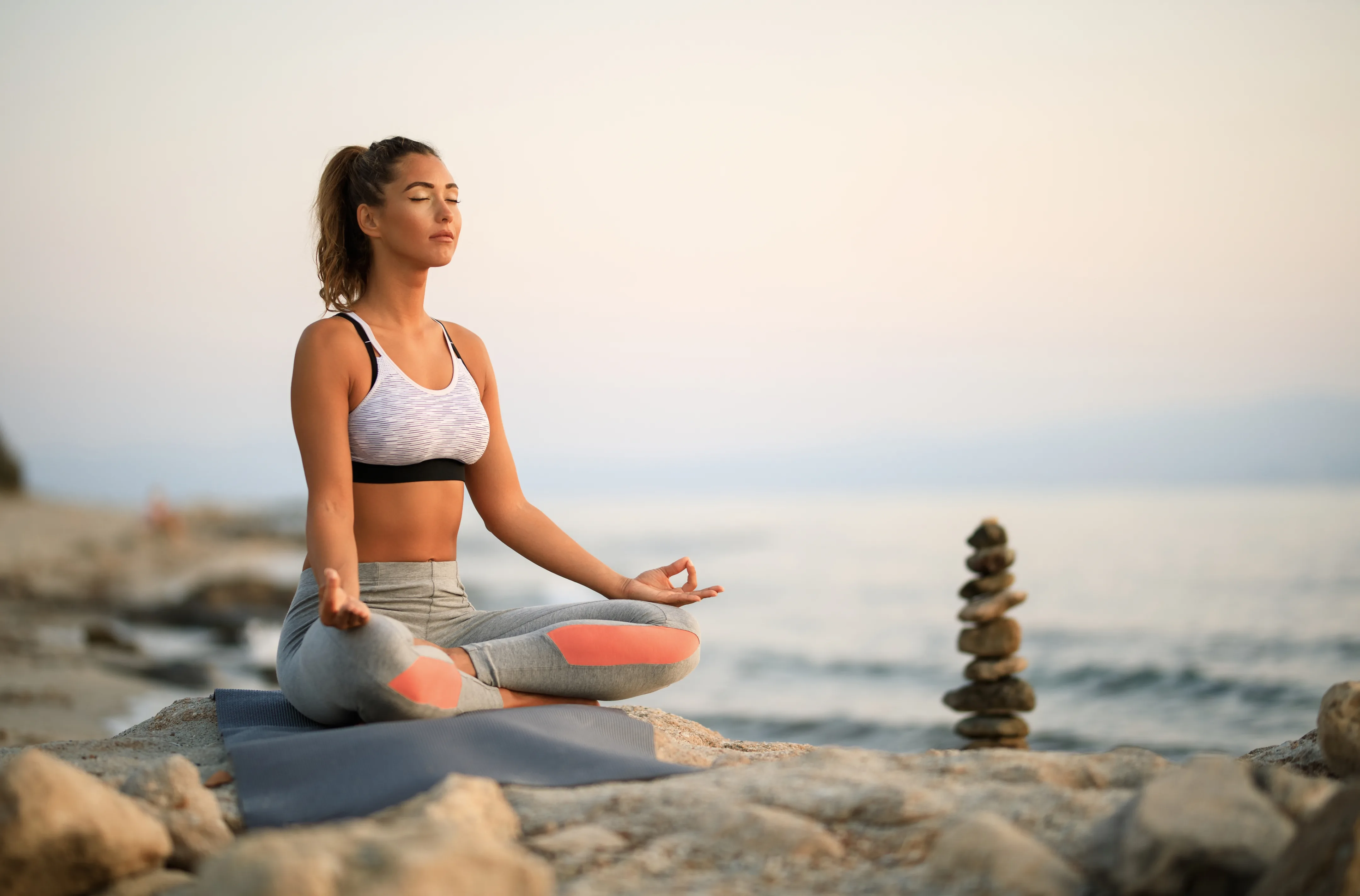 Person meditating on a rock by the sea